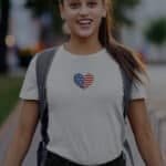 A woman wearing an Independence Day 4th July "HEART" Unisex Heavy Cotton Tee.