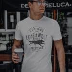 A man wearing a OUTDOOR LONELY WOLF Hunter Unisex T-Shirt that says Lonely Wolf Adventure.
