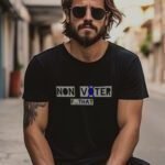 A bearded man with sunglasses sits on a street wearing the "Non Voter | Elections 2024" black unisex T-shirt, which features the bold message, "NON V⚕️XER F...THAT.