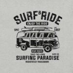 This vintage-style graphic tee features a surf van with surfboards on top, promoting "Surf & Ride" and "Surfing Paradise." This Unisex Heavy Cotton Tee includes a phone number, a reference to Blue Beach, and the establishment year of 1957.